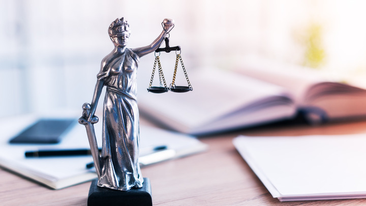 Eine Figur der Justitia steht auf einem Schreibtisch