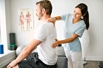 Physiotherapeutin und Patient in einem Therapieraum