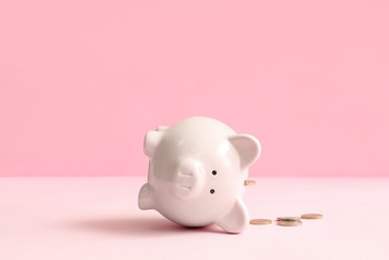 Sparschwein liegt auf der Seite, Münzen daneben